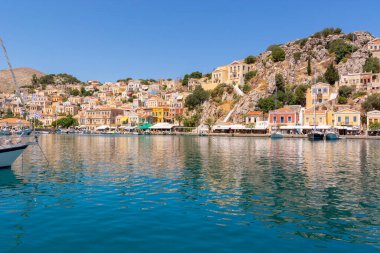 Yunanistan 'ın güzel Suriye adası turkuaz bir koy ve renkli Dodecanese mimarisi ile
