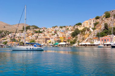 Yunanistan 'ın güzel Suriye adası turkuaz bir koy ve renkli Dodecanese mimarisi ile