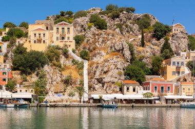 Yunanistan 'ın güzel Suriye adası turkuaz bir koy ve renkli Dodecanese mimarisi ile