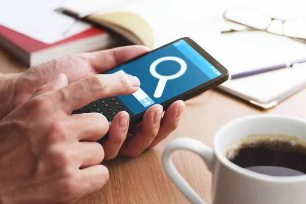 Primer plano de manos masculinas tocando la pantalla del teléfono inteligente para la búsqueda de Internet en la mesa . — Foto de Stock