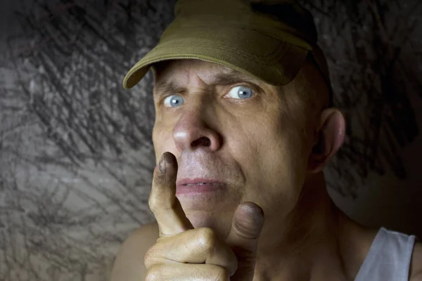 A  nervous man warning with a dirty finger, studio portrait with selective focus