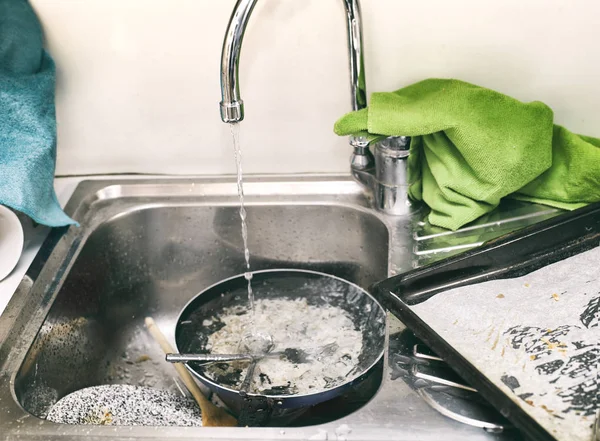 Messy kitchen sink loaded with dirty dishes, filtered shot
