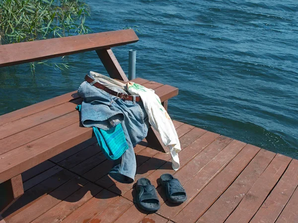 A bench on a jetty with abandoned personal belongings, outdoor shot