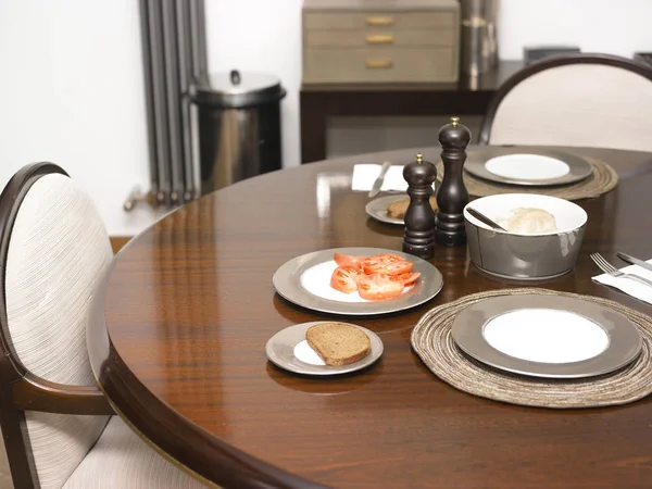 Round wooden table served indoors with dishware and silverare, interior shot