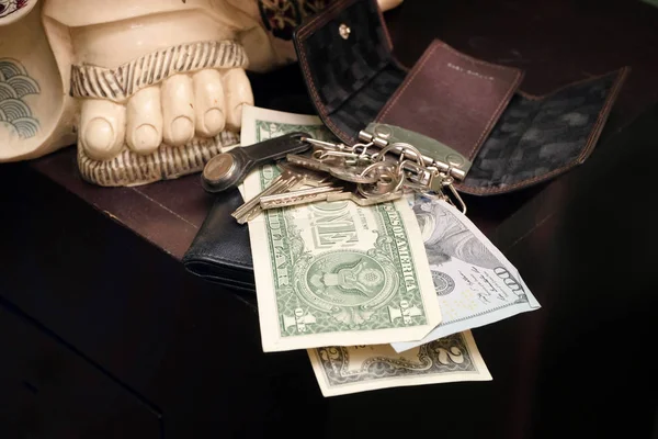 Bunch of keys, wallet and cash on a table, indoor closeup