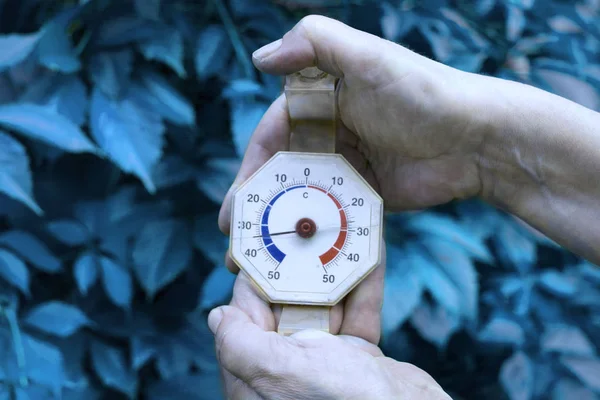 Filtered close-up of the bare hands holding a gauge indicating low temperature