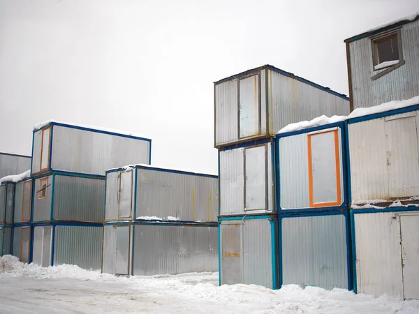 Outdoor warehouse with a stack of metal containers or houses, winter scene