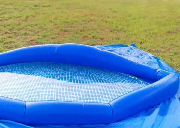 Inflatable portable swimming pool on a green lawn, outdoor shot
