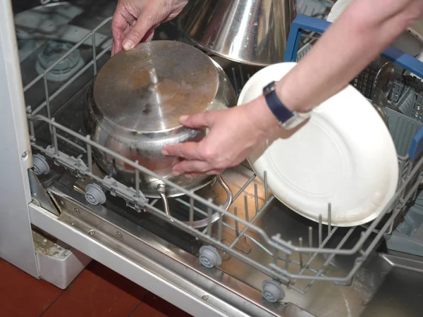 Hands arranging dishware in open dishwasher — Stock Photo, Image