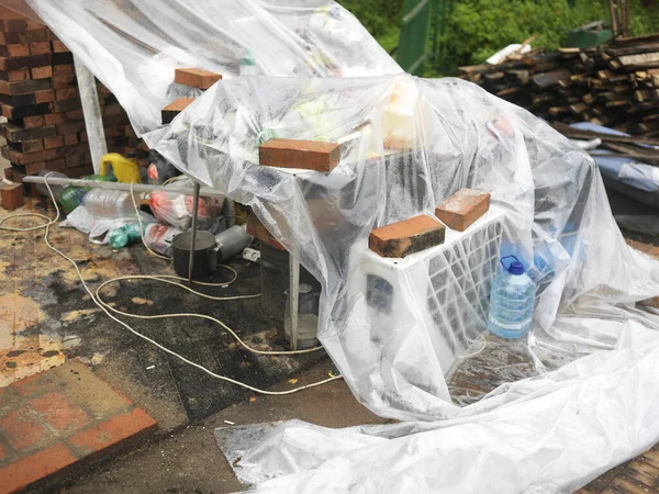 Cellophane foil covering household stuff abandoned under rain, outdoor closeup