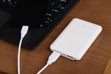 şarj Smartphone ahşap arka plan üzerinde beyaz harici pil (güç banka)