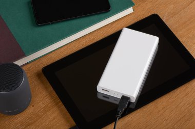 Tablet pc ahşap arka plan üzerinde şarj beyaz harici pil (güç banka)