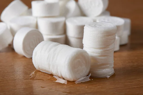 a heap of compressed coin tissues and expanded tissue after wet, on a wooden background