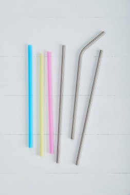 yeniden kullanılabilir paslanmaz çelik çubuk ve tek kullanımlık renkli payet ahşap bir masa üzerinde