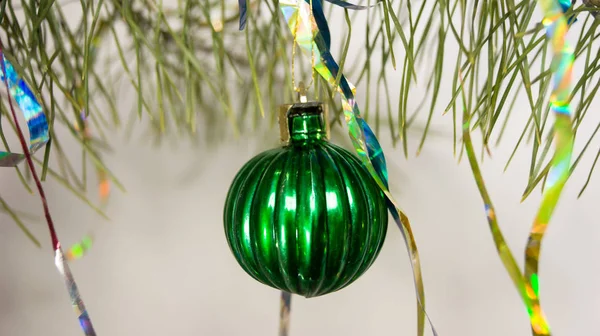 green Christmas ball close-up on a pine branch