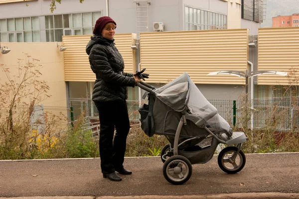 散歩のためのベビーカーで赤ちゃんを持つ少女 ストック写真