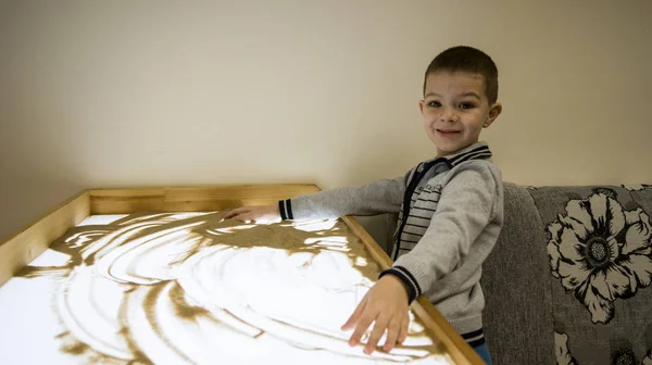 the child at the table for sand therapy