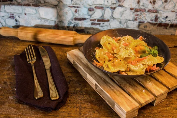 siyah taş tabakta somon ile doldurulmuş makarna