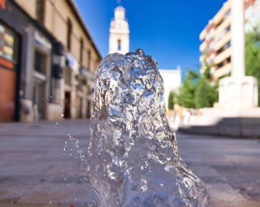 Arka planda bir kilise olan çeşmeden bir su püskürtüsü.