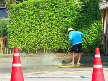 person holding water hose and cleaning city street