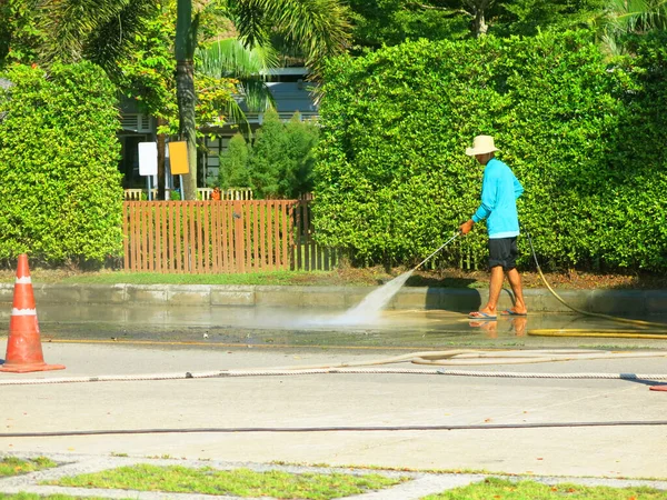 Person Holding Water Hose Cleaning City Street — Zdjęcie stockowe