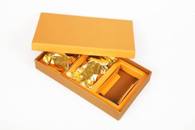 Beyaz arkaplanda izole edilmiş altın ambalaj kağıdıyla kahverengi kutunun yakın plan görüntüsü