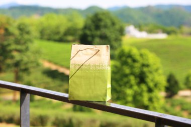 Brown paper bag on fence in garden.