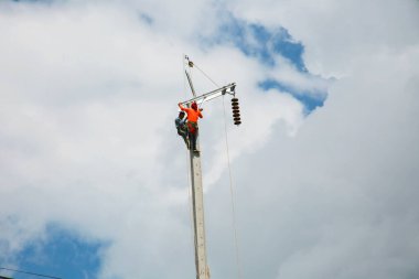 construction worker on electricity pole with a blue sky background
