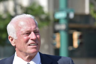 Şehir merkezinde gülümseyen yetişkin üst düzey iş adamı