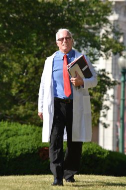 Yakışıklı kıdemli erkek doktor yürüyüş önlük giyen gülümseyen