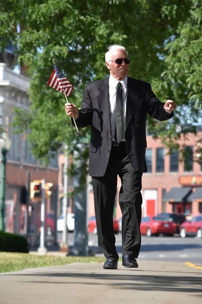 歩道の上を歩くアメリカ国旗を持つアダルト シニア男性政治家肖像画 — ストック写真