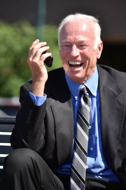 Cep telefonu ve mutlu oturma kullanarak yetişkin üst düzey iş adamı