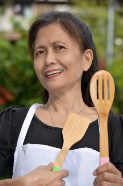 Mutfak gereçleri ile gülümseyen kıdemli azınlık kadın aşçı