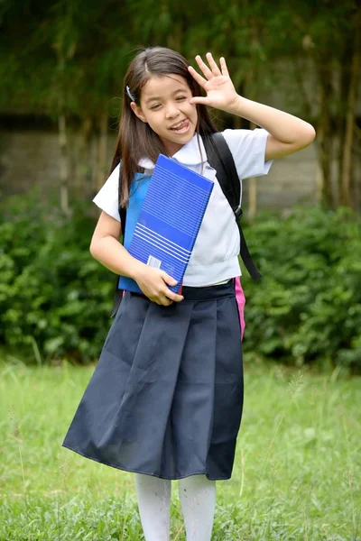 年轻的女学生制作有趣的脸穿校服与书籍 — 图库照片