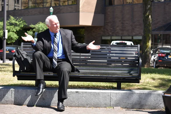 Upset Senior Person Wearing Suit And Tie Sitting On Bench
