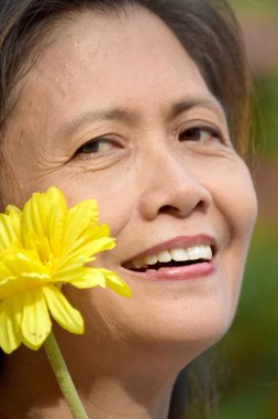 Asyalı kadın kıdemli bir çiçek ile gülümseyen