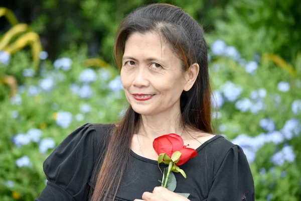 Gelukkig gepensioneerde gevarieerde vrouwelijke Senior vrouw met een bloem — Stockfoto