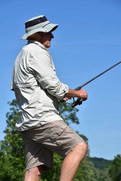 Pescador masculino mais velho ereto com haste e pesca do carretel — Fotografia de Stock