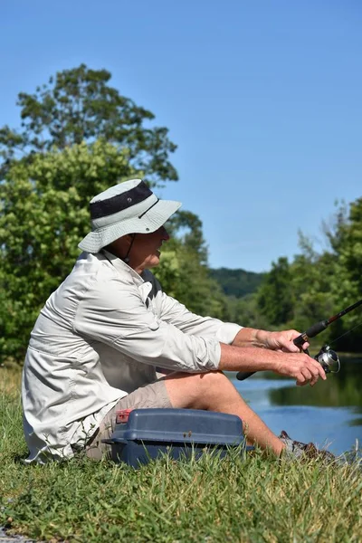 Пенсіонер чоловічий рибалка розслабляючий з стрижня і котушки риболовлі — стокове фото