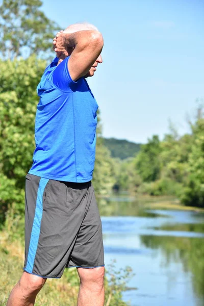 Atletico maschio anziano stretching all'aperto — Foto Stock