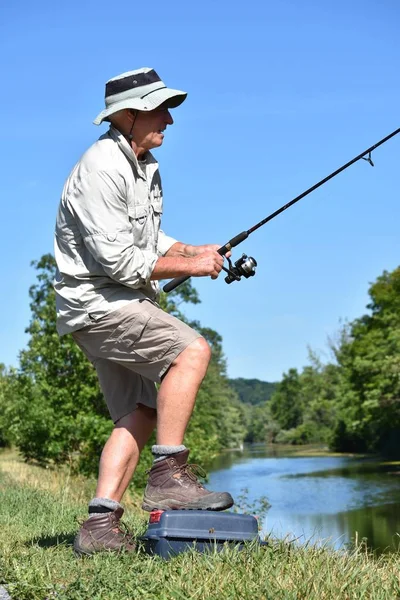 Aposentado masculino pescador de pé com haste e carretel de pesca — Fotografia de Stock