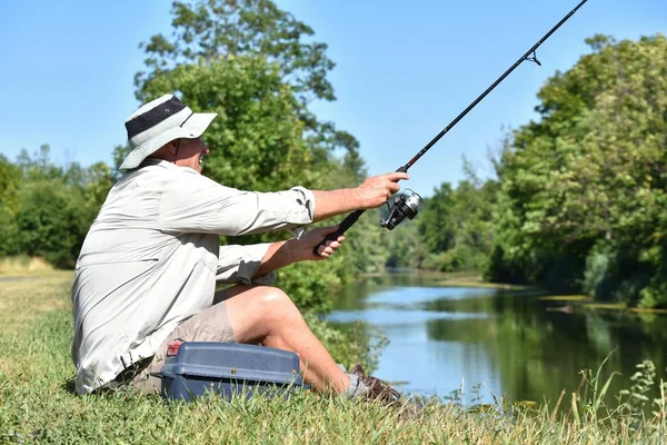 Velho aposentado masculino pescador sentado com pesca Rod — Fotografia de Stock