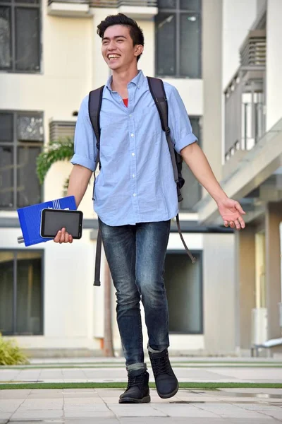 Счастливый юный студент с книгами, идущими по кампусу — стоковое фото