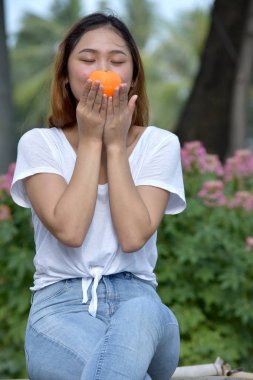 bir portakal tutan genç kadın