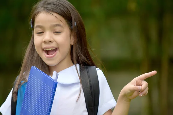 Mignon minorité fille étudiant pointant du doigt portant uniforme scolaire avec cahiers — Photo