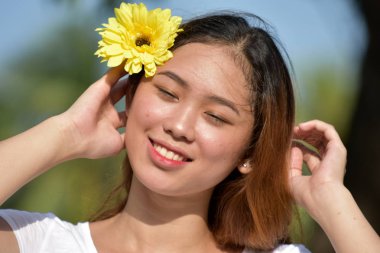 Çekici Asyalı Kadın Bir Daisy ile Gülümsüyor