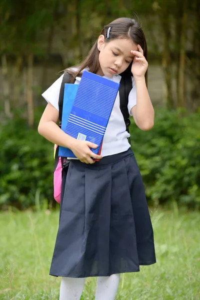 Deprimerad kvinnlig elev klädd i uniform med böcker — Stockfoto