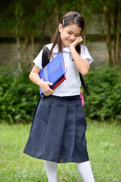 本で学校の制服を着て泣くかわいいアジアの女子学生 — ストック写真
