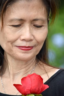 Gülleri olan mutsuz yaşlı Asyalı kişi.