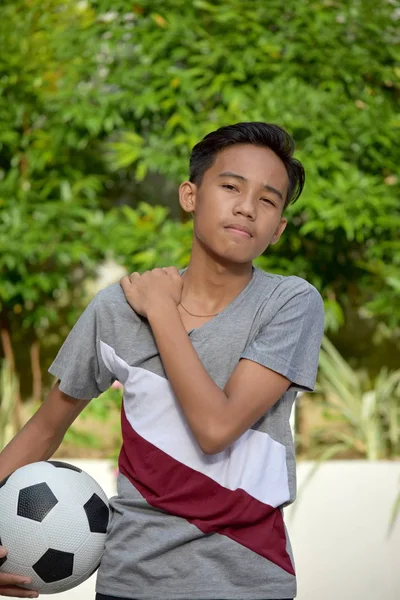 Joven jugador de fútbol masculino filipino dolorido con balón de fútbol — Foto de Stock